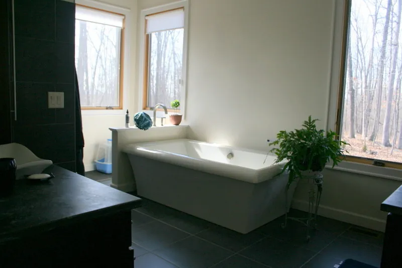 Bathroom with a freestanding soaking tub below two windows.