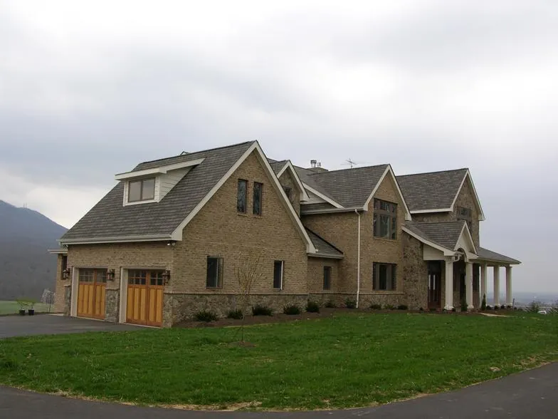 Two-story stone and siding home with dormers and wood-look garage doors.
