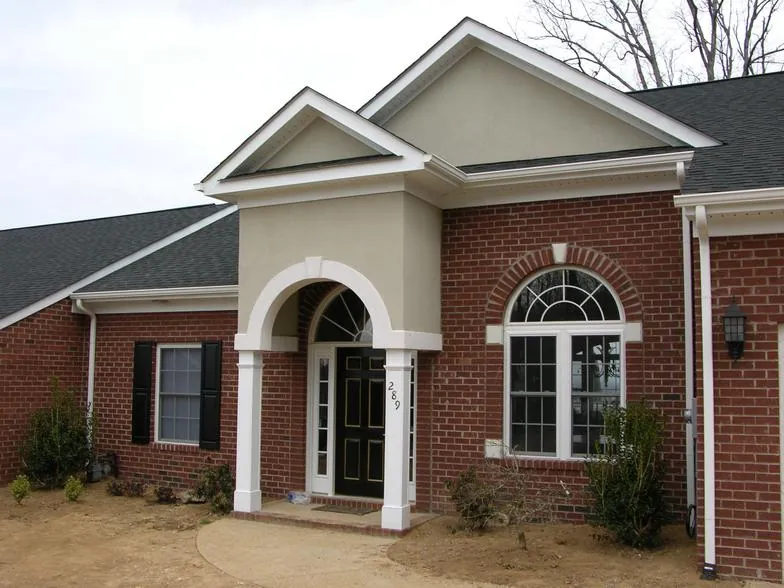 Brick home with an arched entry framed by white columns and an arched window.