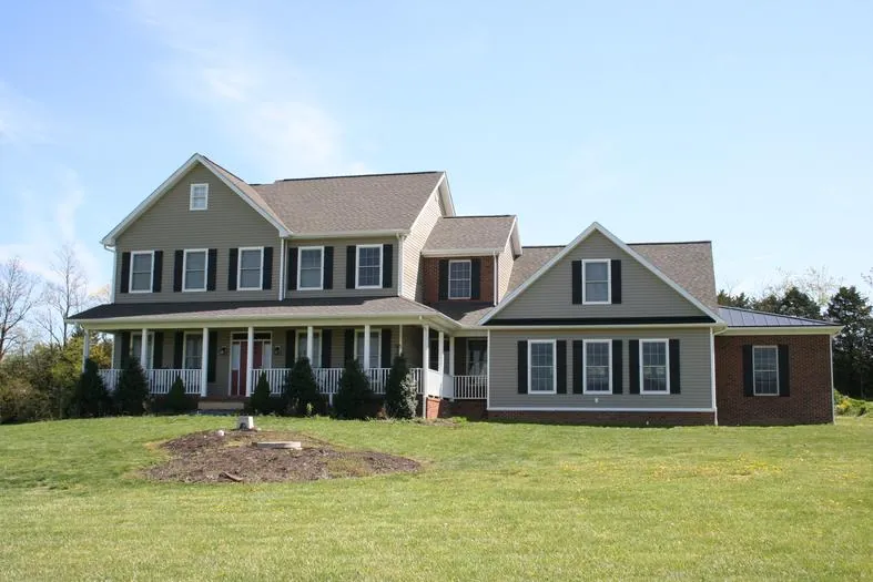 Two-story home with a full-width front porch and a side wing, on an open lawn.