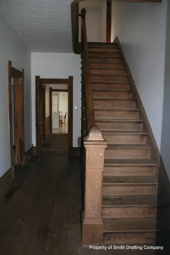Center hall with a straight wooden stair, a newel post, and wood door trim.