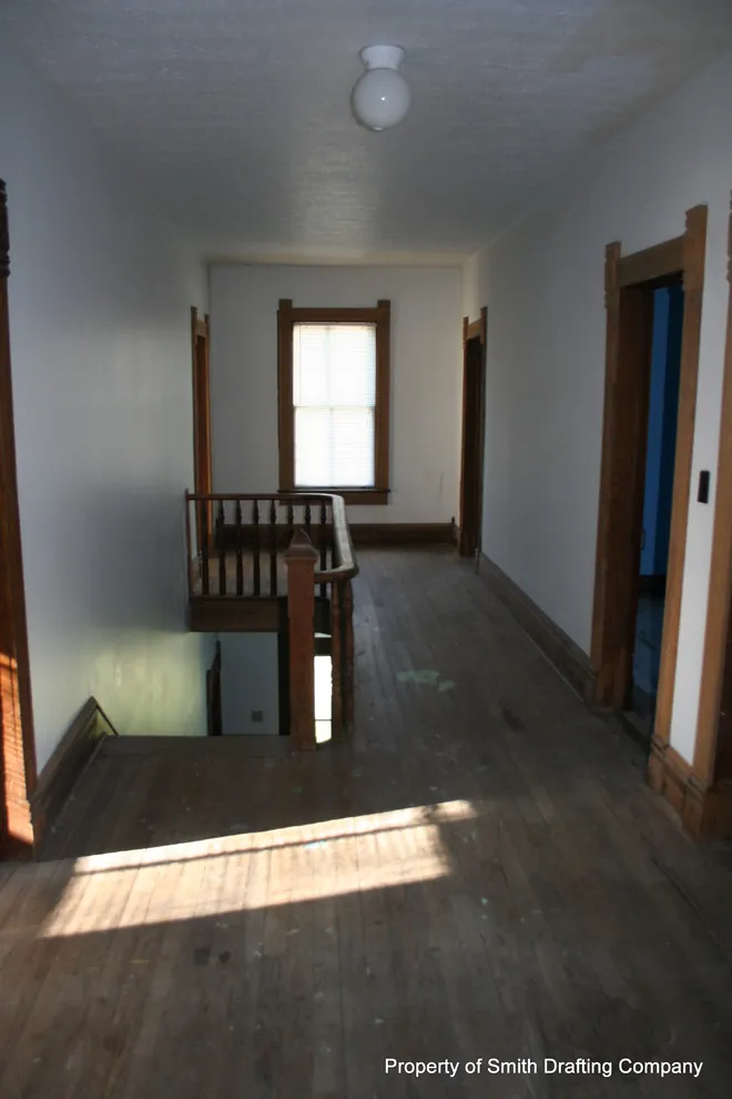 Upper hall looking toward a window, with the railing around the stair opening.