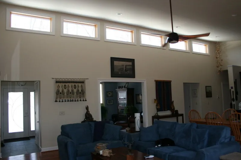 Great room with a row of clerestory windows high on the wall and a ceiling fan.