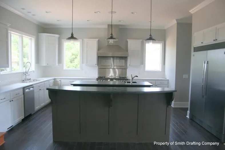 Kitchen with white cabinets, pendant lights, and a large dark island.