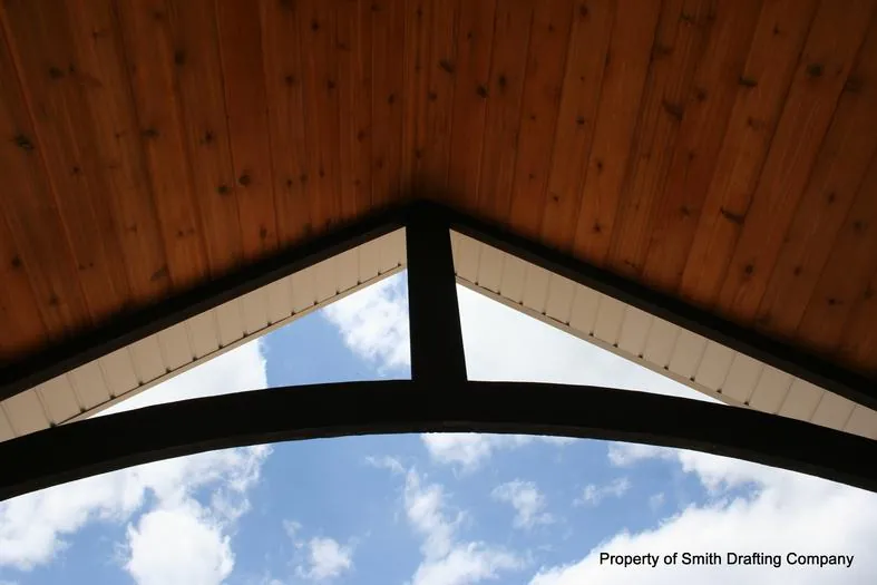 Looking up into a gable with a wood plank ceiling and a dark timber truss.