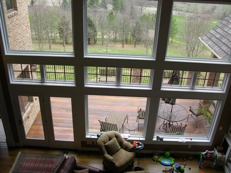 Tall window wall with French doors looking out to a deck and the yard.
