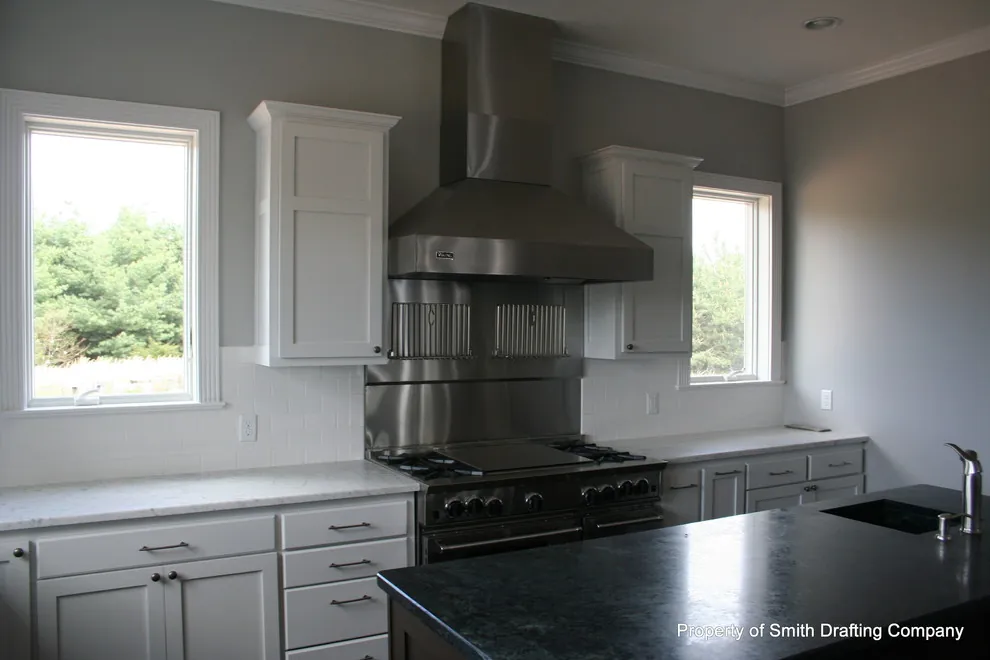 The same white kitchen from a second angle, showing the range hood and a window.